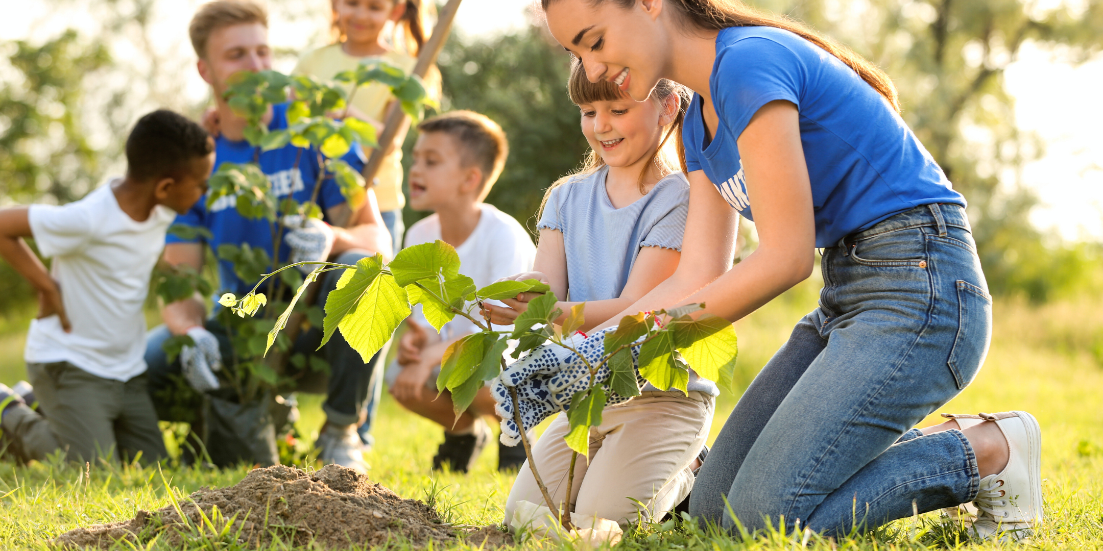 older woman helps girl plant a tree