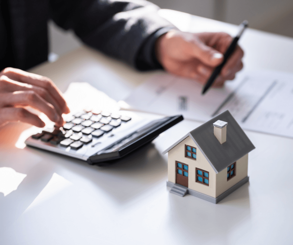 hand calculating numbers on a calculator next to a toy house